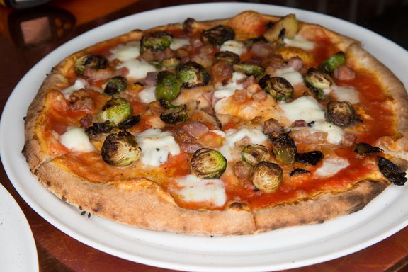 Pizza studded with Brussels sprouts is one inventive pie that can be found at East Village Bohemian Pizzeria. Photo by Brandon Scott.