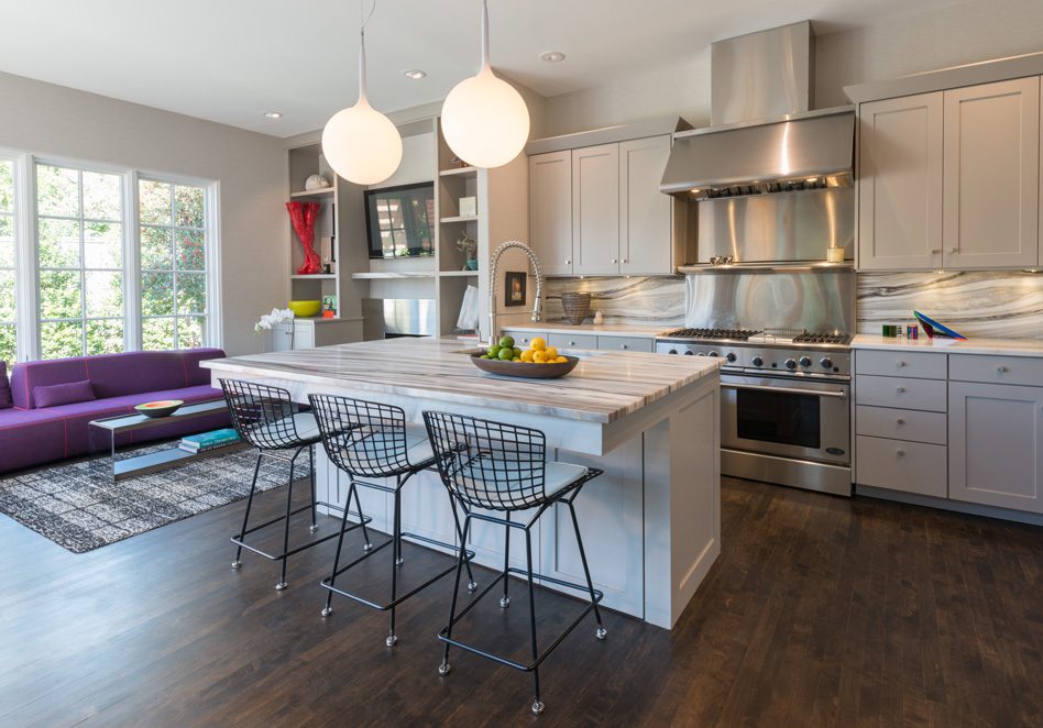 in The kitchen, existing birch cabinets were painted gray, and new countertops and backsplash were added. Photo by Nathan Harmon.