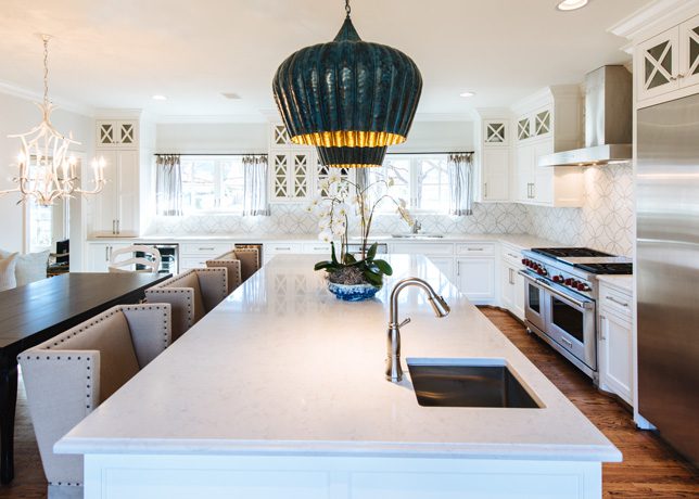 The kitchen’s upper cabinets faced in glass have recessed lighting, which displays the homeowner’s china collection. Matching pendant lights that hang over the island provide that extra “Ah ha!”, says Welch. Caesarstone quartz counters contribute to the open, airy feel of the room.