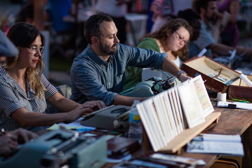 Chad Reynolds (center) writes made-to-order poems at a recent H & 8th event. Photo by Brent Fuchs.