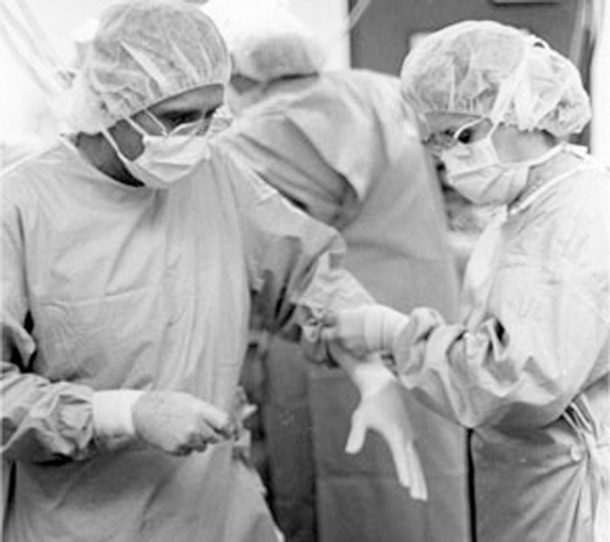Dr. Nazih Zuhdi, left, slips on gloves before a heart transplant in the ‘80s. Photo courtesy INTEGRIS.