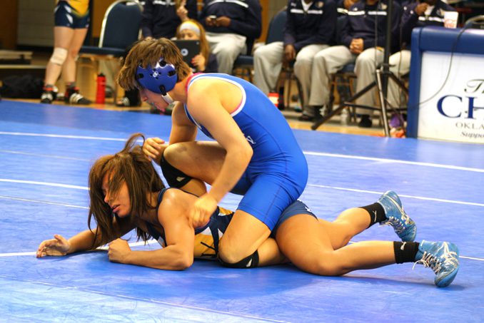 Oklahoma City Univeristy wrestler Emily Webster (top) grapples with an opponent during the 2013-2014 season. Photo by Rich Tortorelli.