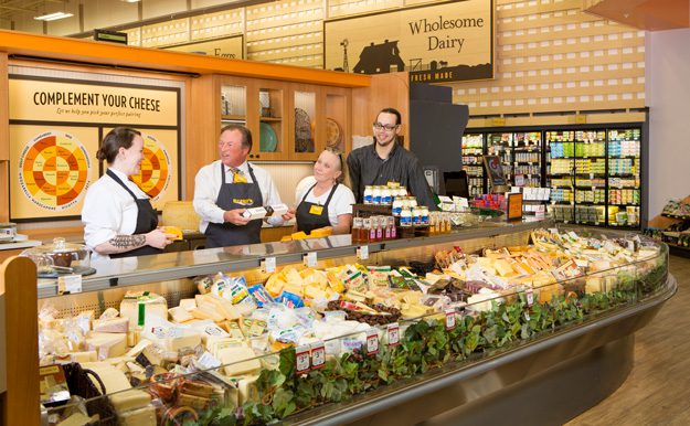 Reasor discusses products with employees at the cheese counter of the Brookside location of Reasor’s foods.