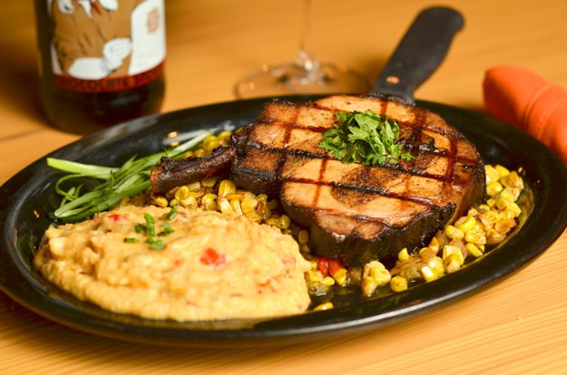 Chorizo and cornbread stuffed pork chop with skillet corn and hominy grits. Photo by Dan Morgan.