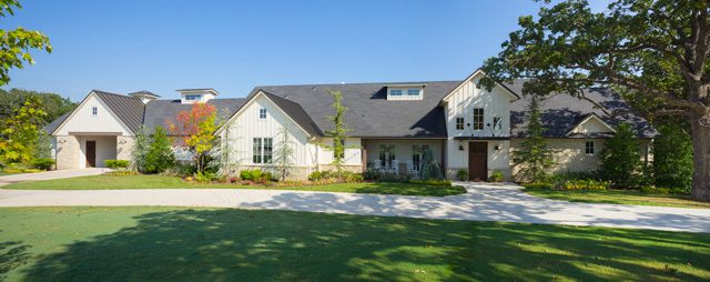 The exterior of this modern farmhouse features Buss Luders stone from Richburg Stone in downtown OKC. A board and batten style is used near the front door and complements the standing seam roof in a similar pattern.