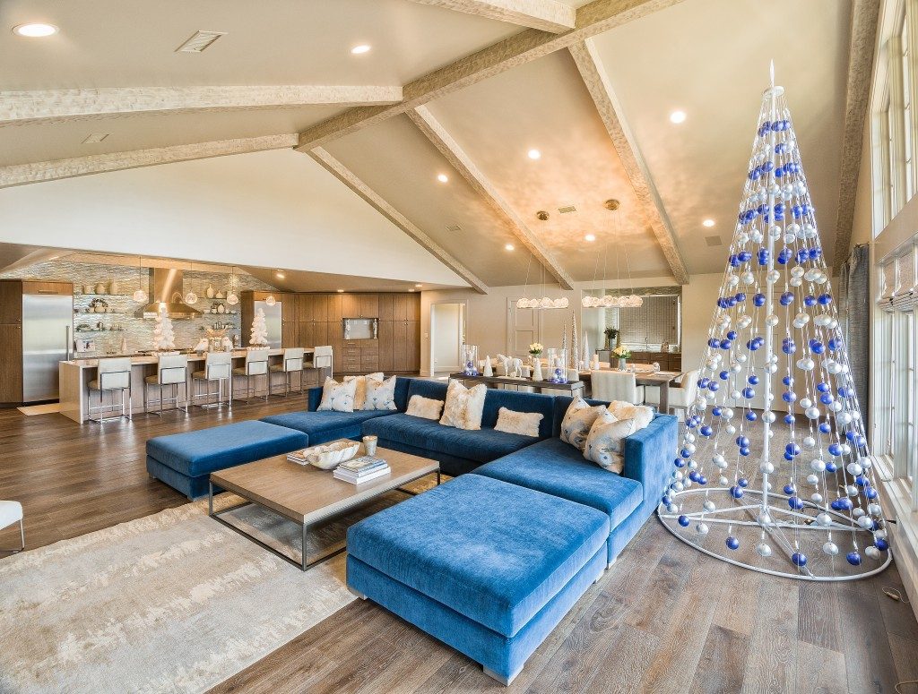A pyramid metal tree dressed with blue and silver ornaments, complements the blue sofa in the spacious living/dining/kitchen great room area. Photos by Scott Johnson, Hawks Photography