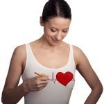 Heart beat. Young woman drawing a heart on her t-shirt
