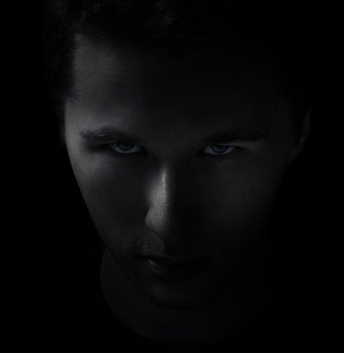 dark young adult man portrait fade in black