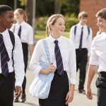 Group Of Teenage Students In Uniform Outside School Buildings