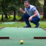 a mini-golf player looks at the result of a blow to the side of