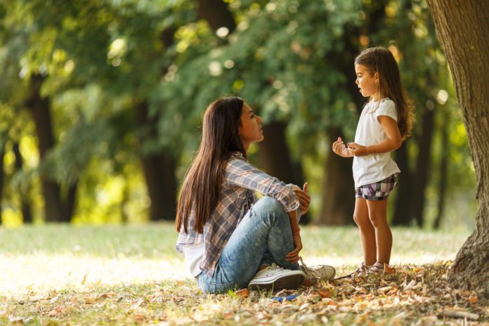 Mother holding her daughter and playing around the park on beaut